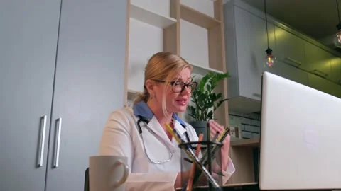 Senior blonde doctor is explaining something to the patient online during a Stock Footage 146513281