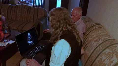 Senior brother and sister using laptop at home into living room for review .. Stockbeeldmateriaal 288047342