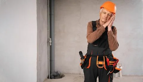 Senior builder on construction site standing wearing safety helmet showing .. Stock Photos