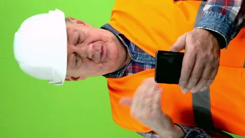 Senior builder in hardhat talking with phone webcam talking about things at work Stock Footage 252293761