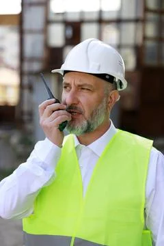 Senior builder man, inspector in protective hardhat giving commands for builders Stock Photos