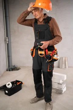 Senior builder man in uniform with hard hat standing in repairing house, ti.. Stock Photos