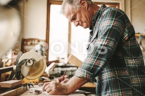 Senior carpenter planning his work at carpentry Stock Photos