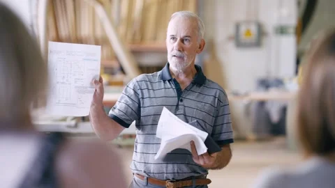 Senior carpenter presenting project blueprints in workshop Stock Footage 337882322
