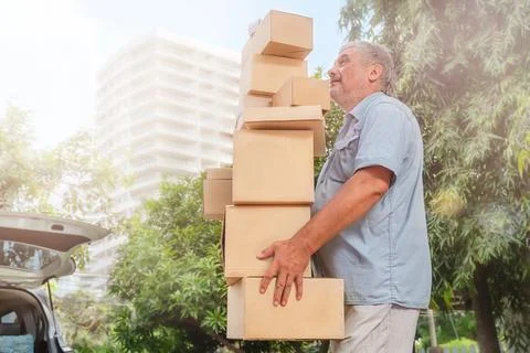 Senior carries a high stack of cardboard boxes for moving Stock Photos