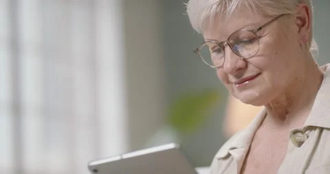 Senior caucasian lady using a tablet computer at home. Mature woman surfing web Stock Footage 139367908