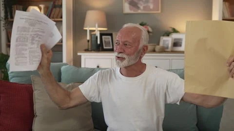 Senior caucasian man open mail letter or document envelope at home Stock Footage 251570518