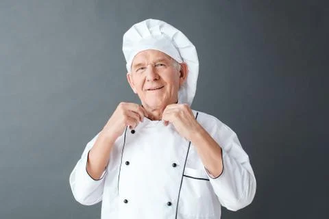 Senior chef studio standing isolated on gray holding collar looking camera Stock Photos