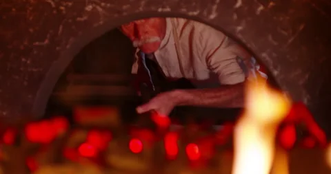 Senior chef using peel to take freshly baked pizza out of stone oven. Mature Video stock 154329268