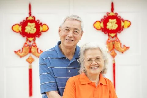Senior chinese couple outside home decorated with welcoming feng shui banners Stock Photos