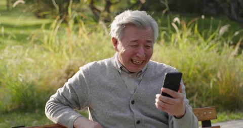 Senior Chinese man using smart phone in the park,4K Stock Footage 227130113