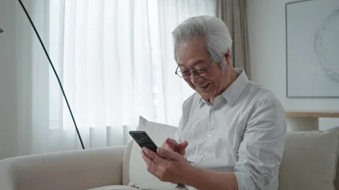 Senior Chinese man using smart phone at home,4K Stock Footage 244042672