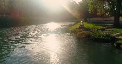 Senior citizen reading by the river at sunset Stock Footage 124381913