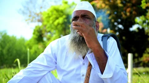 Senior Citizen Smoking While Sits on Ground Stock Footage 290118010