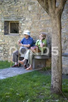 Senior citizens resting and making cell phone call on Plaza Mayor, in Ainsa, Stock Photos