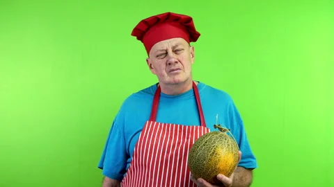 Senior cook in apron sniffs ripe melon and makes delicious, perfect gesture. Stock Footage 250290794