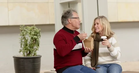 Senior couple approaching bench, greeting and sitting, using chopsticks and Stock Footage 343239286