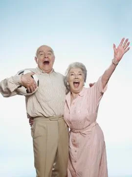 Senior couple cheering as man is holding football Stock Photos