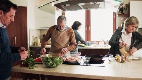 Senior couple cooking dinner together with friends at home. Stock Footage