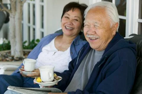 Senior couple drinking tea on porch smiling Fotos Stock