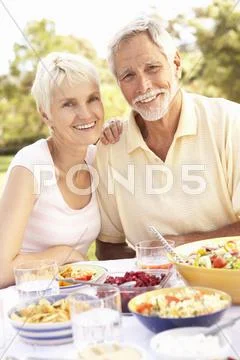 Senior Couple Enjoying Meal In Garden Stock Photos