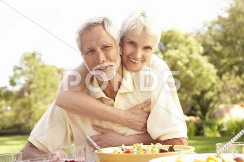 Senior Couple Enjoying Meal In Garden Stock-Fotos