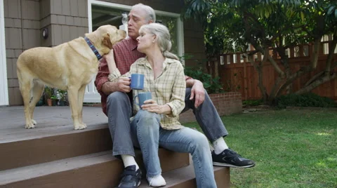 Senior couple having coffee petting dog in their yard Stock Footage