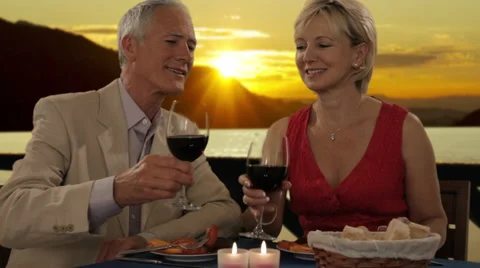 Senior couple having dinner in sunset, toasting each other Stock Footage 43678709