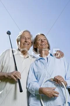 A senior couple holding a golf club and a tennis racket Stock Photos
