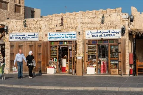 Senior couple holding hands while walking past traditional shops. Stock Photos