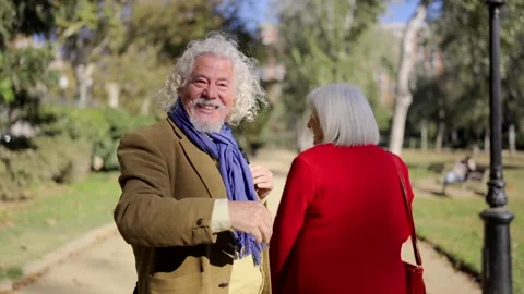 Senior couple inviting to join while walking in a park Stock Footage 260140305