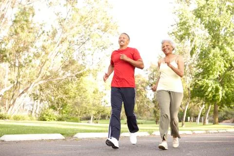 Senior Couple Jogging In Park Stock Photos