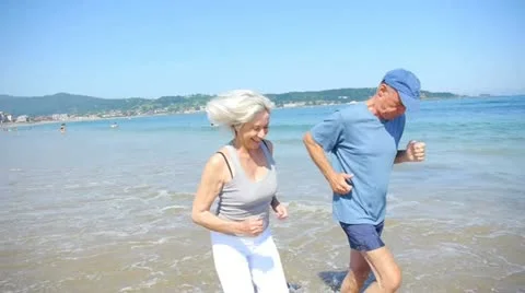 Senior couple jogging on a sandy beach Stock Footage 14829211