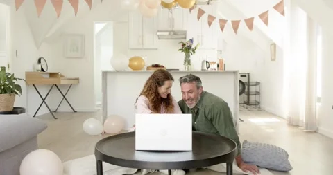 Senior couple kneeling at home using laptop reacting to screen change showing 스톡 동영상 316967871