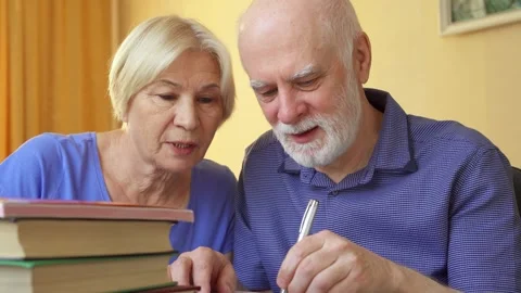 Senior couple learn foreign language grammar. Middle-aged male student writing Stock Footage 131979547