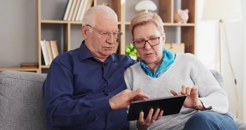 Senior couple learning technology together at home using tablet for Stock Footage 334283476