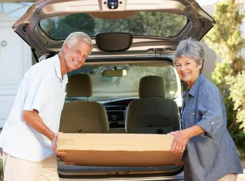 Senior Couple Loading Large Package Into Back Of Car Stockfoto's