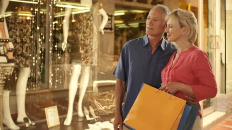 Senior couple looking in shop window in town Stock Footage 43678956