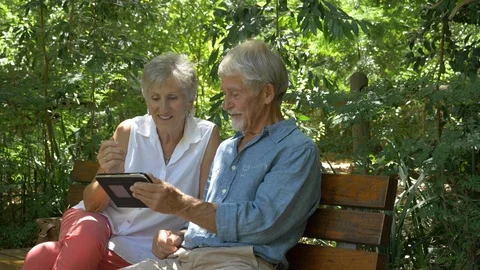 Senior couple looking at tablet computer in a park Stock Footage 91706724