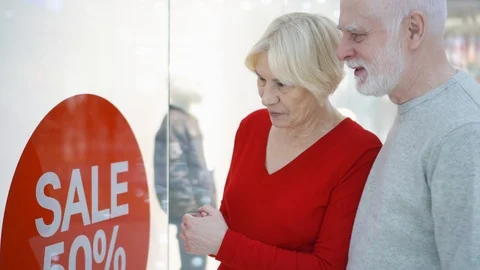Senior couple looking at window shop checking sale prices. Sale and percent sign Stock Footage 88258246