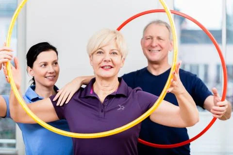 Senior couple in physiotherapy doing exercise with hula hoop Stock Photos