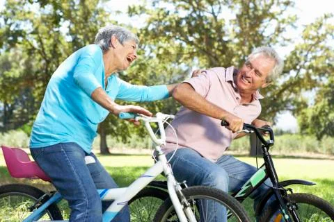 Senior couple playing on children's bikes Stock Photos