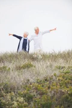 Senior couple pointing at different direction against clear sky Stock Photos