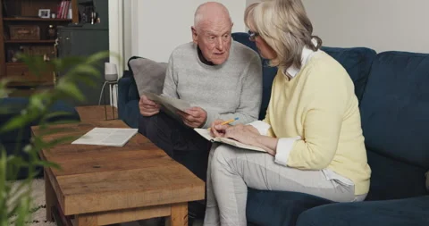 Senior couple reading paperwork, pension report and finance documents in home Stock Footage 307925318