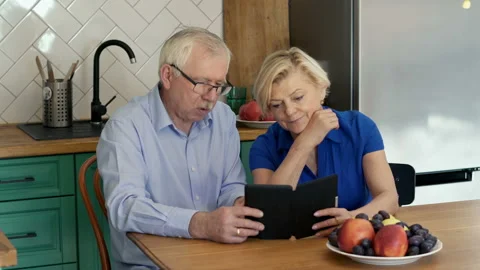 Senior couple reading something on e-book at home Stock Footage 124224610