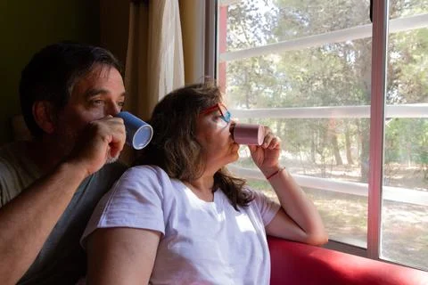 Senior couple relaxing drinking coffee looking outside window Stock Photos