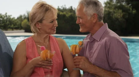 Senior couple relaxing by poolside with drinks Stock Footage 43679255