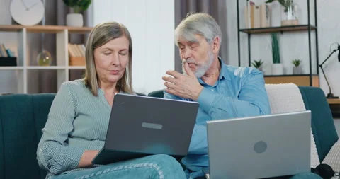 Senior couple resting on comfy couch with personal laptops 스톡 동영상 154177395