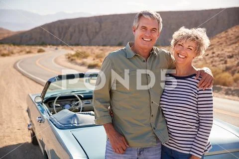 Senior Couple On Road Trip Standing By Car Smiling To Camera