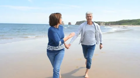 Senior couple running on the beach Stock Footage 63990344